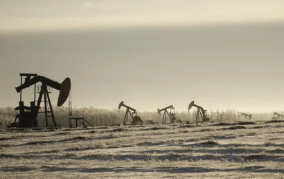 field-with-oil-pump-jacks-surrounded-by-greenery-cloudy-sky-sunlight